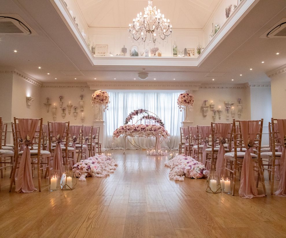 Pink ceremony chair drapes with pink aisle flowers and candles