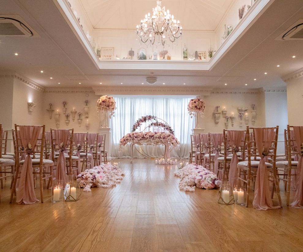 Pink ceremony chair drapes with pink aisle flowers and candles