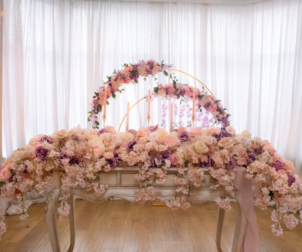 Long pink ceremony top table flowers with pink ceremony arch to hire
