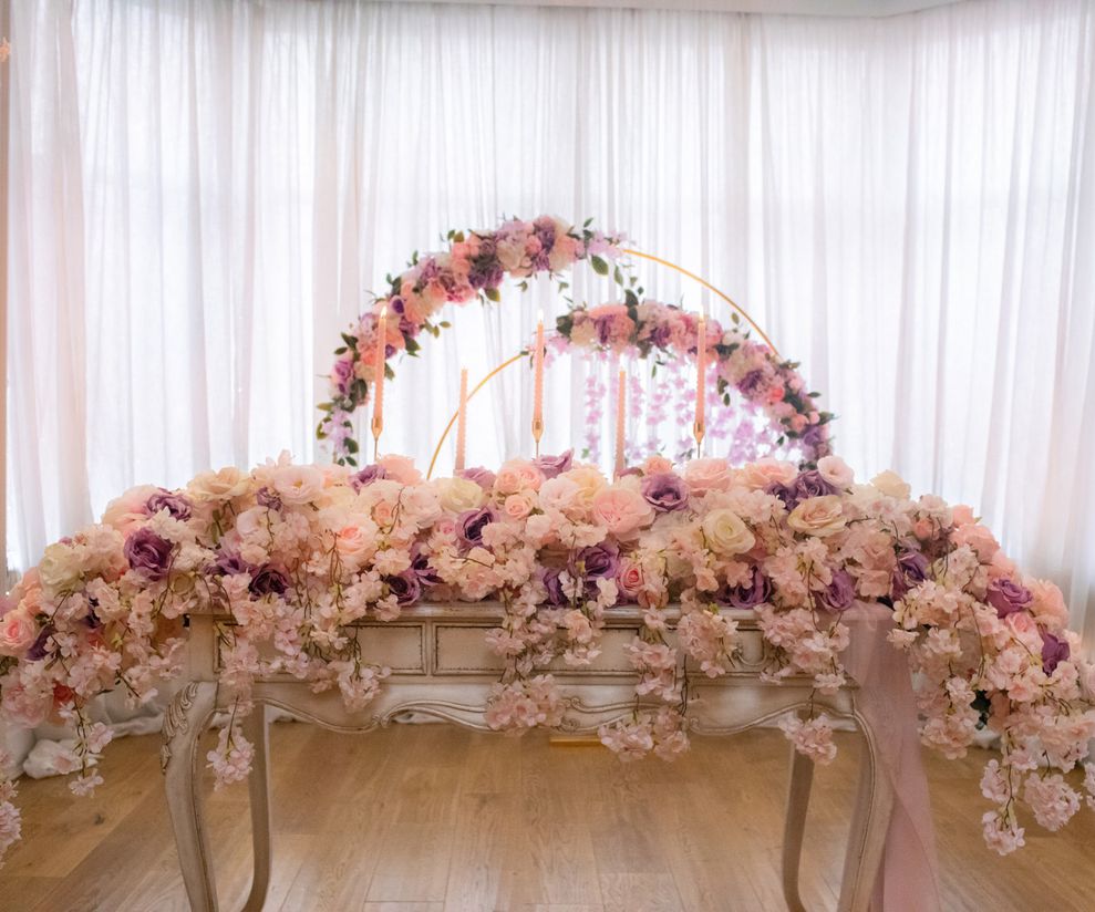 Long pink ceremony top table flowers with pink ceremony arch to hire