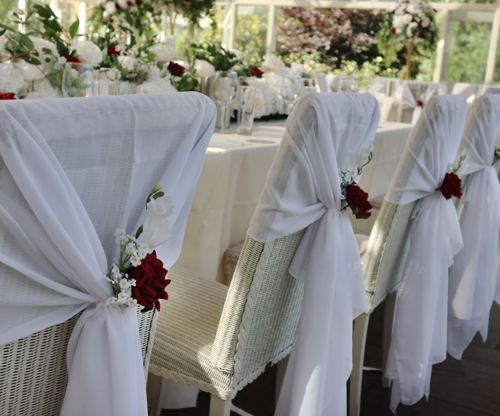White chiffon chair drapes with red roses Cheshire venue dressers