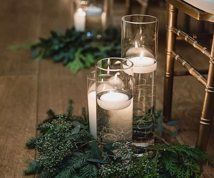 Cylinder vases with floating candles and foliage ceremony aisle